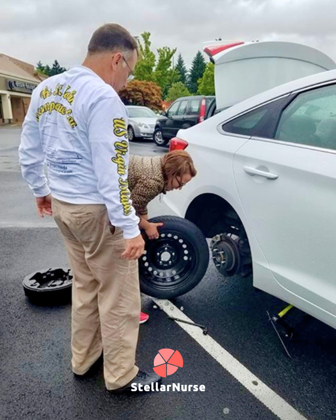 Travel nurse crouched fixing a tire with a spare and jack, on the road bumps of travel nursing