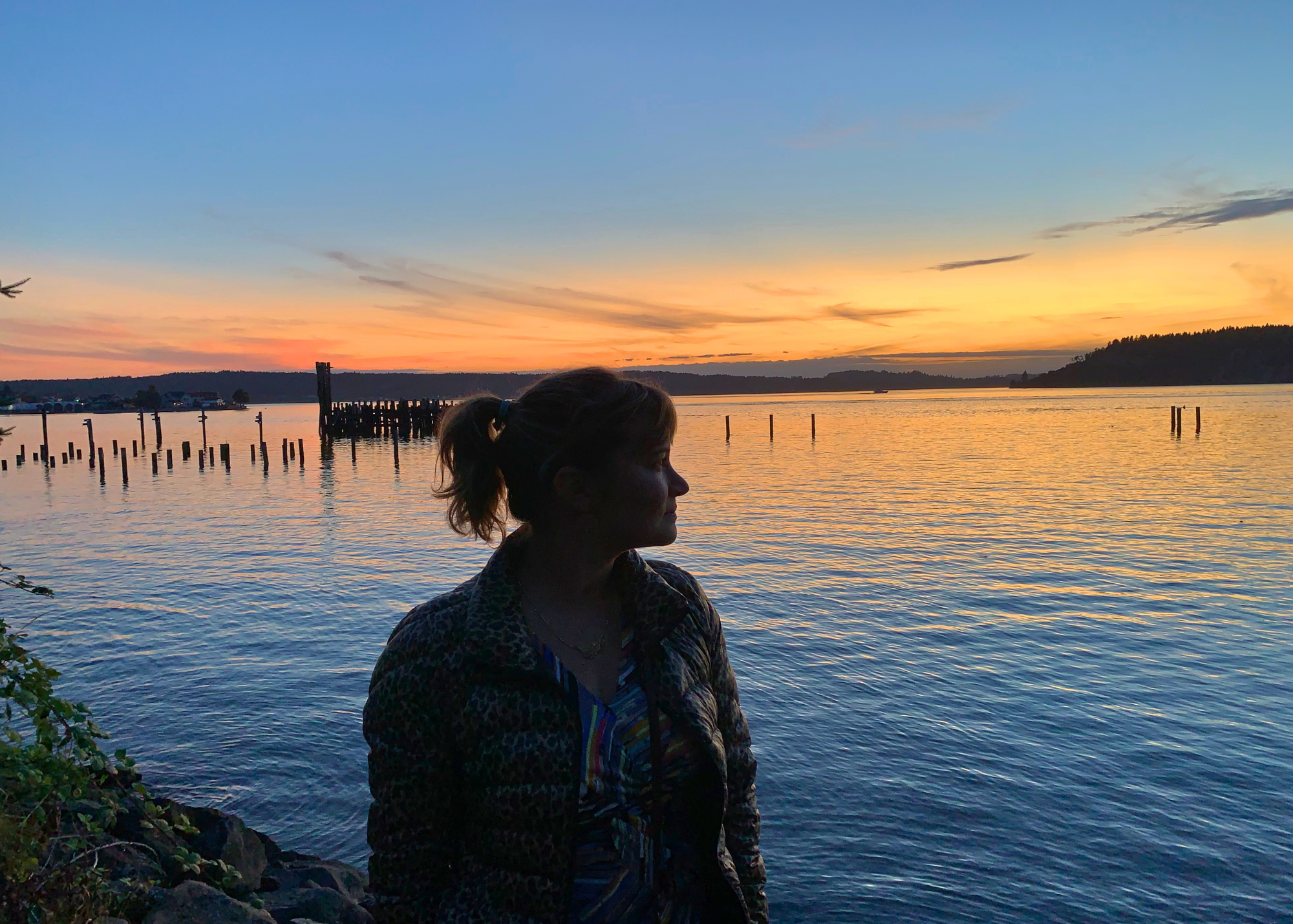 Travel nurse silhouetted against an orange Tacoma sunset over the water